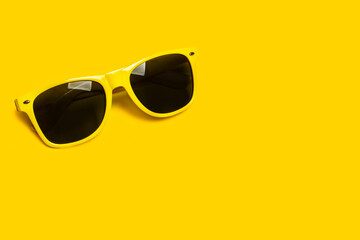 Gafas de sol de plástico amarillas sobre un fondo amarillo brillante liso y aislado. Vista superior y de cerca. Copy space