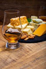 British drinks and food, glasses of Scotch whisky and cheeses collection, blue Stilton, Scottish coloured and English matured cheddar cheeses