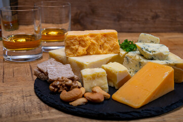 British drinks and food, glasses of Scotch whisky and cheeses collection, blue Stilton, Scottish coloured and English matured cheddar cheeses