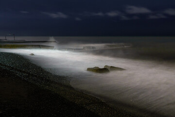 Night photo. Old ruined pier and sea with a full moon. Night Sea Surf.