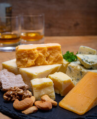 British drinks and food, glasses of Scotch whisky and cheeses collection, blue Stilton, Scottish coloured and English matured cheddar cheeses