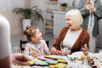 excited woman talking to granddaughter during easter celebration with family.