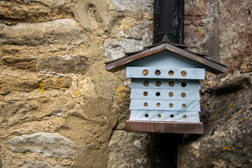 Small bug hotel known as a wildlife hotel or stack, house like construction made to help various insects to survive winter and free to leave in spring, cute litte bug shelter attached to stone wall