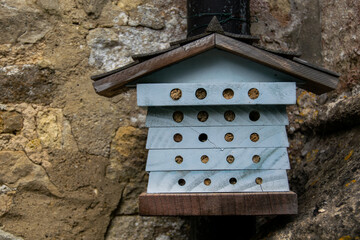 Small bug hotel known as a wildlife hotel or stack, house like construction made to help various insects to survive winter and free to leave in spring, cute litte bug shelter attached to stone wall