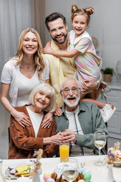 Cheerful Family Looking At Camera Near Table With Easter Dinner.