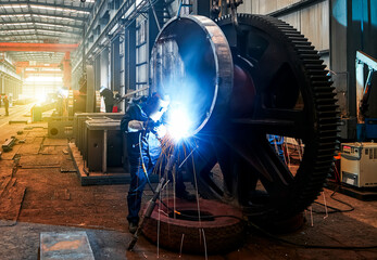Asian worker in professional mask welding steel with welding gun in hand