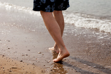 men's feet walk on the sand. close-up without a face. seashore, sandy beach