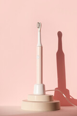 New modern ultrasonic toothbrush. Dental care supplies on cylinder podium on pink pastel background. Oral hygiene, dental and gum health, healthy teeth. Dental products 