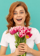 surprised girl with tulip flower bouquet on blue background