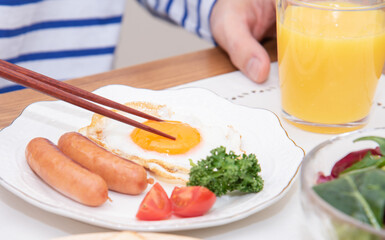 半熟目玉焼きを食べるアジア人の男性