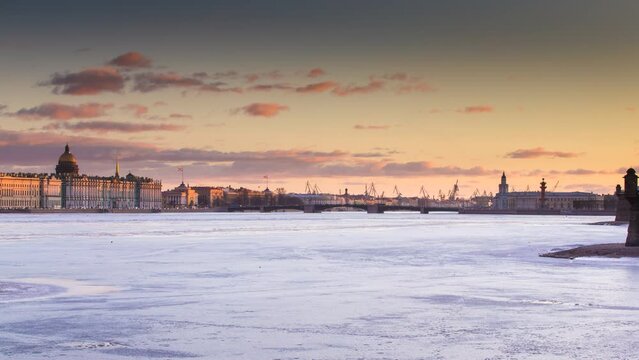 Russia, Saint-Petersburg, Time lapse of the water area of the Neva River at sunset, the Winter Palace, Palace Bridge, the dome of St. Isaac Cathedral, pink clouds, frozen river 