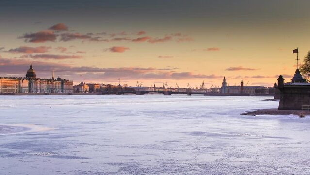 Russia, Saint-Petersburg, Time lapse of the water area of the Neva River at sunset, the Winter Palace, Palace Bridge, the dome of St. Isaac Cathedral, pink clouds, frozen river 