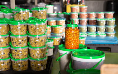 Large assortment of pickled olives in plastic buckets and jars stacked on pallets on artisanal pickles factory