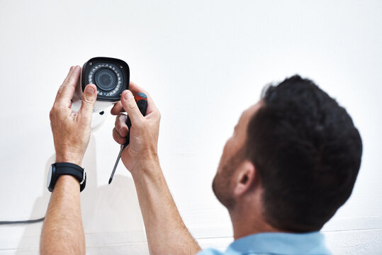 Can you guys see me down there. Shot of a mature man installing a security camera on a building.