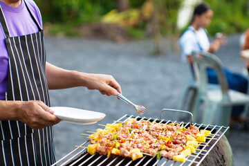 An Asian man grills a barbecue at a house party for dinner in the house.