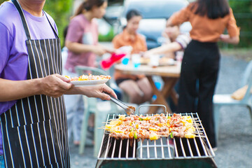 An Asian man grills a barbecue at a house party for dinner in the house.