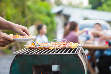 An Asian man grills a barbecue at a house party for dinner in the house.