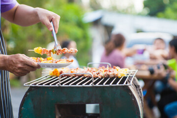 An Asian man grills a barbecue at a house party for dinner in the house.