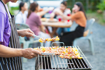 An Asian man grills a barbecue at a house party for dinner in the house.