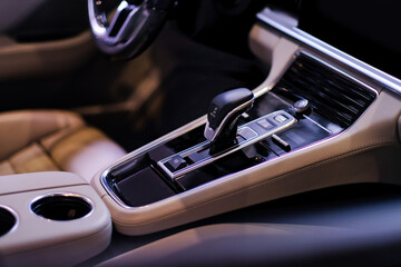 Modern luxury car inside interior with gear shift, automatic transmission, buttons, cup holders and...