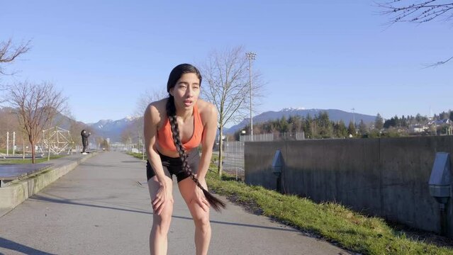 Young fit female runner fatigued stops to breathe walks off 