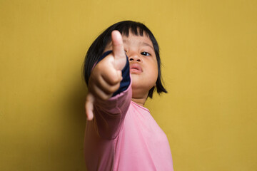 Asian little girl with ok sign gesture tumb up isolated on yellow background
