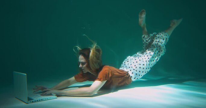 Happy young determined beautiful freelance manager business woman dives underwater to work with laptop slow motion.