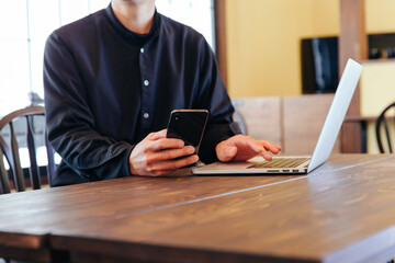 Fototapeta premium スマホを持ってパソコン操作する男性 jobs
