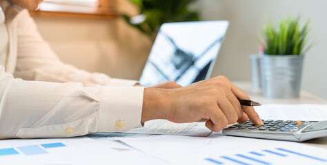 A man uses a calculator to calculate company profits from statistical graphs. Business men looking at charts, spreadsheets, bank accounts, statistics, economy, data analysis, stock exchange
