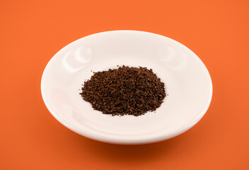 coffee grounds on plate with orange background
