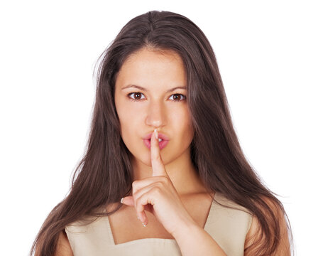 Ssh, lets keep it between us.... A young businesswoman with her finger on her lips while isolated on white.