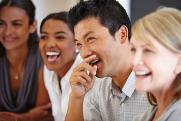 Sharing the joke. Shot of an Asian man laughing at a table with his coworkers out of focus. - obrazy, fototapety, plakaty