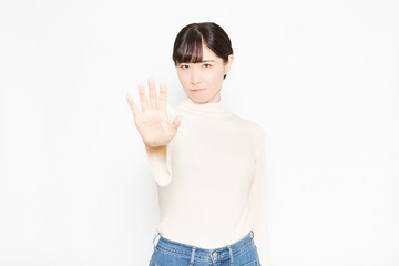 白い背景の前に立ってNGのジェスチャーをする女性