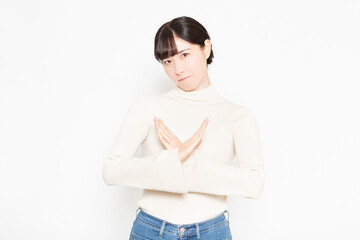 白い背景の前に立ってNGのジェスチャーをする女性