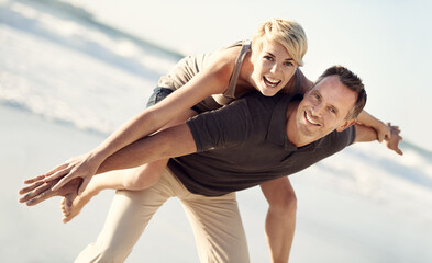 Forever playful. A husband giving his wife a piggyback ride on the beach.