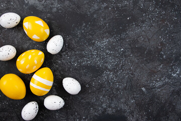Fototapeta na wymiar Yellow easter eggs on black background, happy easter concept. Festive background, flat lay.
