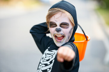 Trick or treat. Little boy dressed up as a skeleton fro Halloween trying to scare you.