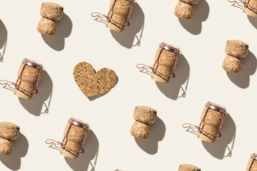 Creative pattern with champagne cork and heart on beige background with hard light and shadows at sunlight. Champagne love concept, bottle cap from sparkling wine and metal wire muselet