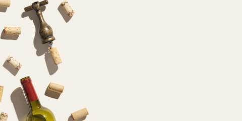 Background with wine corks, old corkscrew, wine bottle  on beige pastel color with shadow at sunlight, copy space. Wide banner with natural wooden bottle cap, metal vintage opener, copyspace