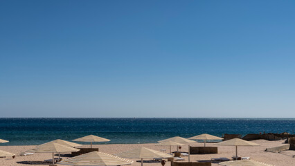 Clear blue sky and turquoise Red sea. On the sandy beach there are umbrellas , sun beds. Egypt....