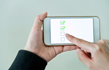 Closeup of hand holding smartphone with vote button on the screen