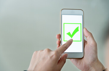 Closeup of hand holding smartphone with vote button on the screen