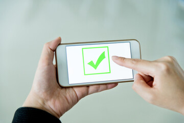 Closeup of hand holding smartphone with vote button on the screen