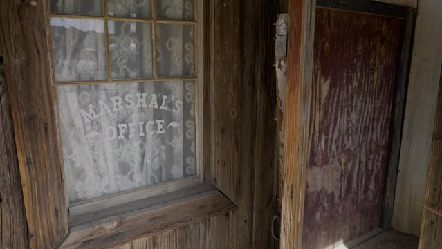 This panning video shows an old marshals office door and window.