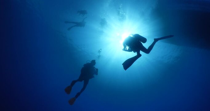 scuba divers coming down descending scenery underwater sun beams and rays sun shine silhouette scenery