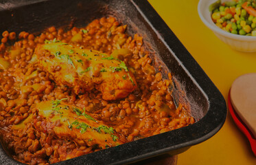 Spiced chicken and lentil tray bake,garnished with herbs.