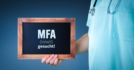 MFA (m/w/d) gesucht! (Medizinische Fachangestellte). Arzt zeigt Schild/Tafel mit Holz Rahmen....