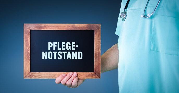 Pflegenotstand (Personalmangel). Arzt zeigt Schild/Tafel mit Holz Rahmen. Hintergrund blau