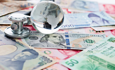 Stethoscope and glass globe on many banknotes