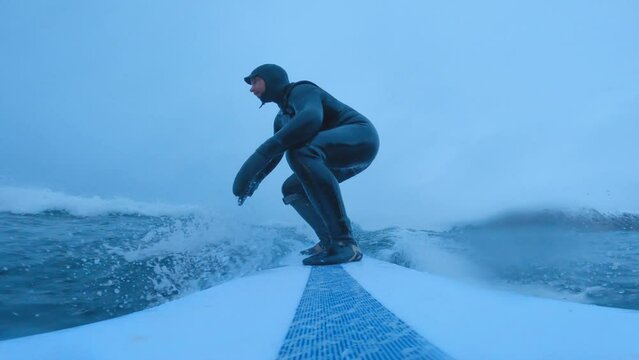 Surfing in the Arctic North of Norway, Scandinavia, Blue light, moody surf with a longboard. Winter surf